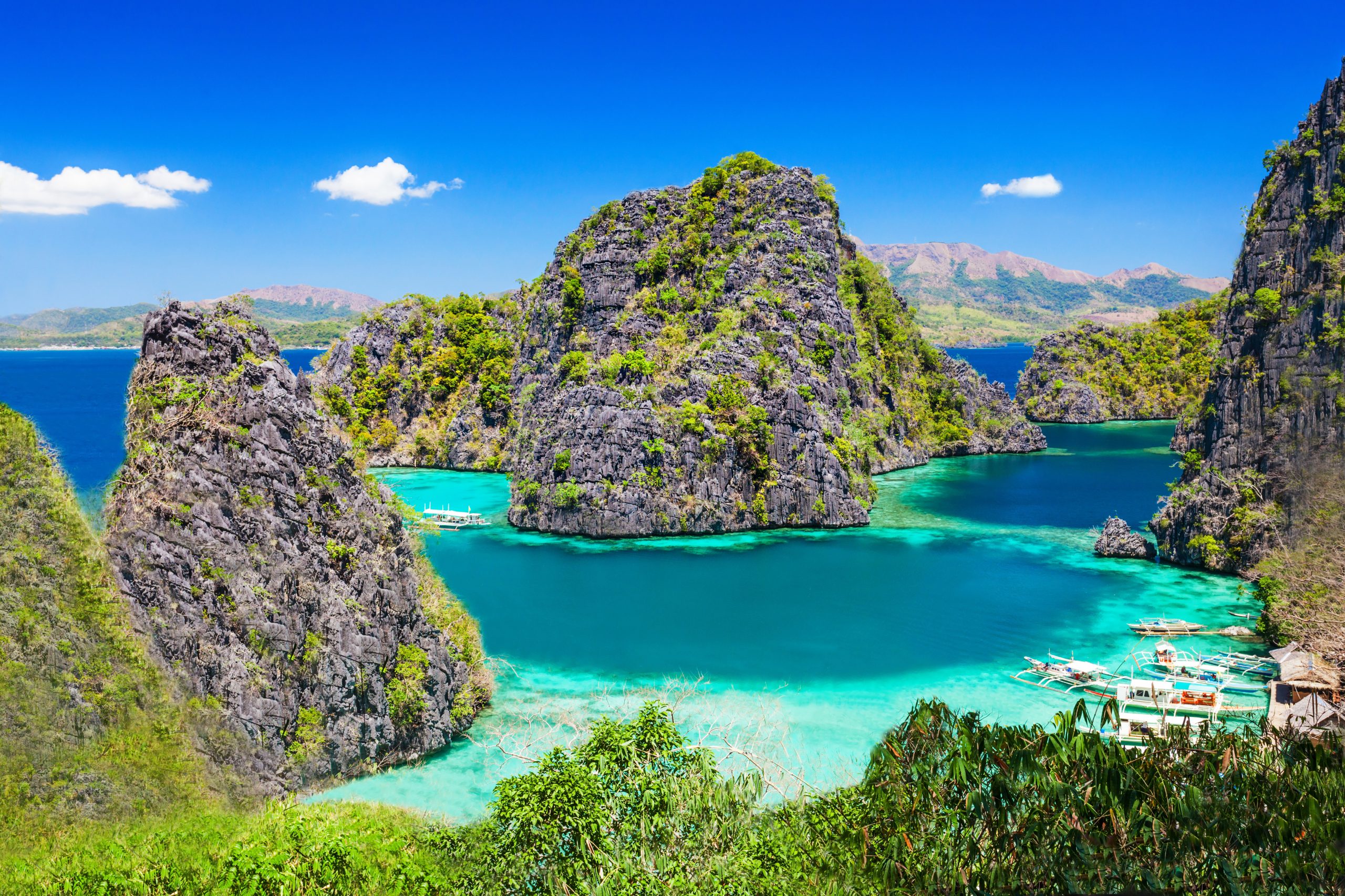 Limestone islands and island-hopping boats in a turquoise lagoon in Palawan