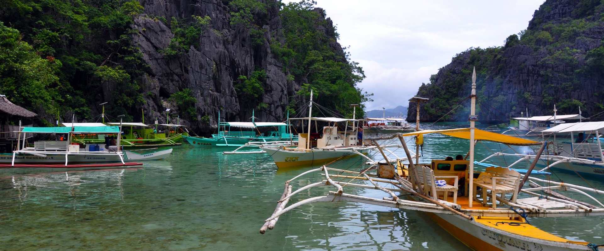 Island-hopping boats moored below limestone cliffs in El Nido, Palawan