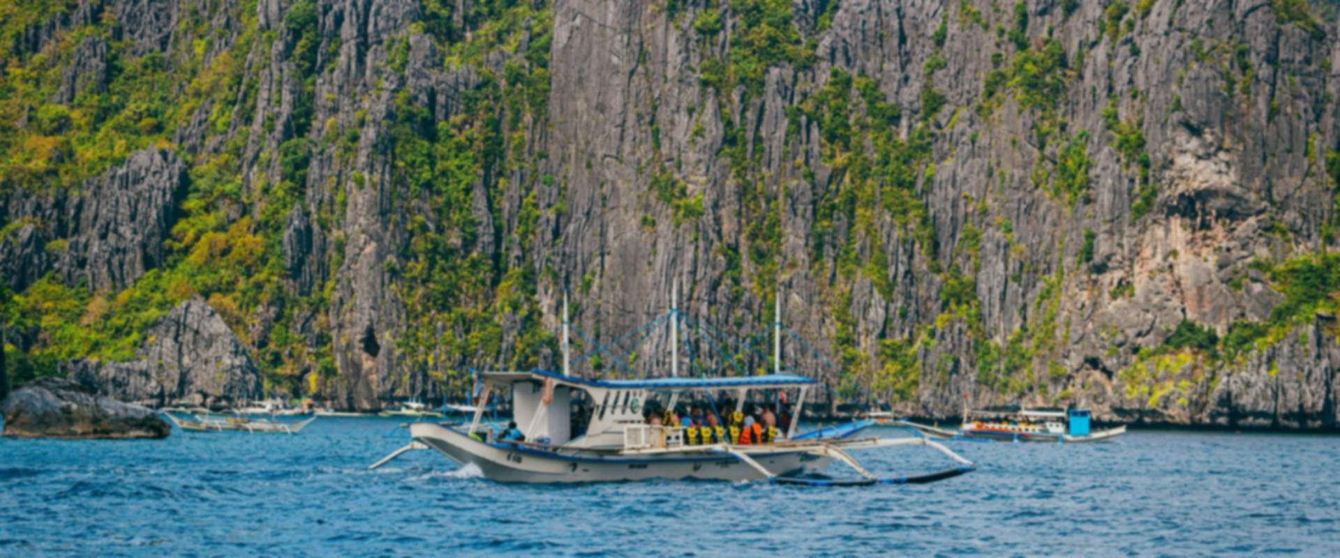 A traditional boat below limestone cliffs in El Nido, Palawan