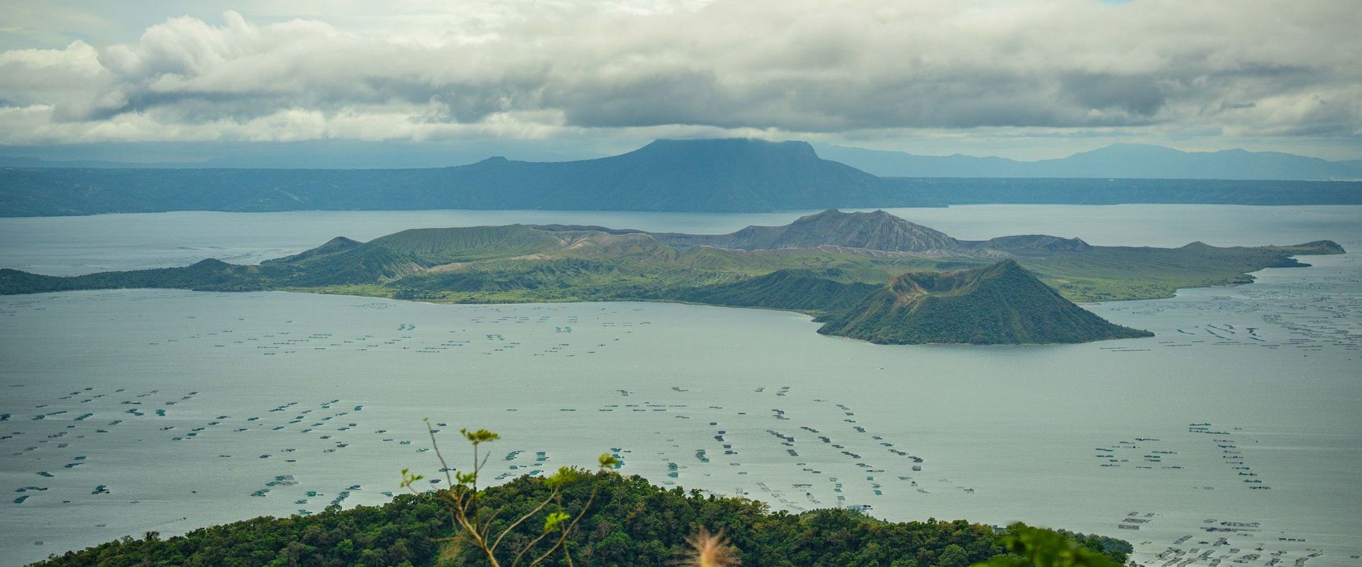 Taal Volcano island and Taal Lake seen from the ridge under a cloudy sky