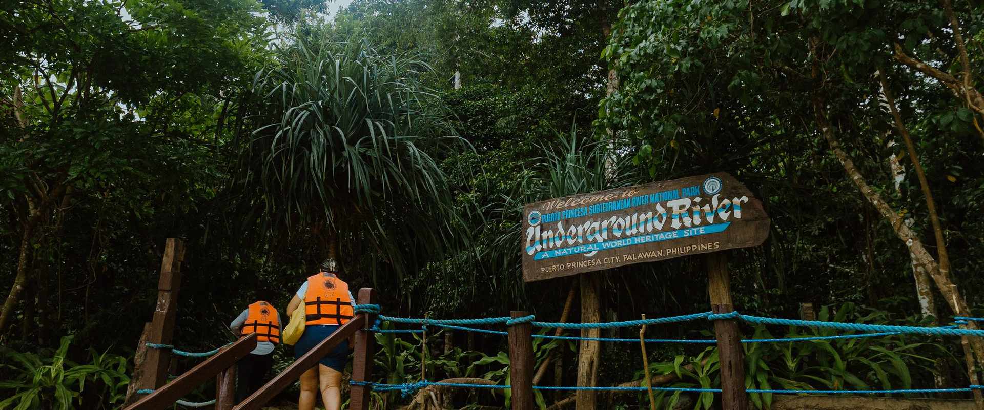 Visitors in life vests walking to the Puerto Princesa Underground River sign in Palawan
